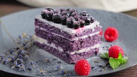 Eating a piece of velvet cake sprinkled with powdered sugar, taking a bite of desert with fork, a person tasting pastry decorated with lavender and currant berries, slow motion close up 4k video clip