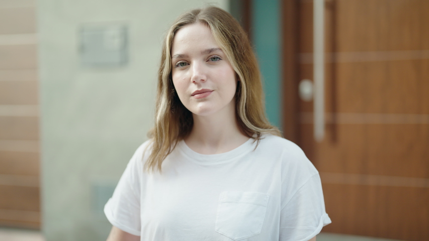 Young caucasian woman smiling confident holding key of new home at street