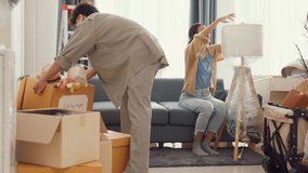 Young happy Asian couple help each other moving box full of stuff unpacking furniture on sofa couch in living room at new house. Husband and wife move new house, Apartment Rent And Ownership Concept. - Powered by Shutterstock - Get 15% off with code: PIKWIZARD15