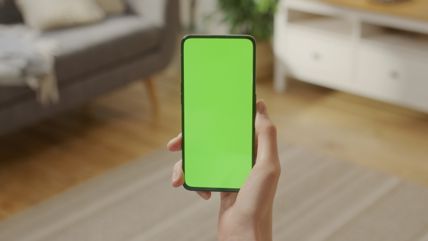 Handheld Camera: Point of View of Woman at Phone with Green Screen for Copy Space. Chromakey Mock Up Without Tracking Markers. Close Up. Girl is Surfing Content With Touching Swiping Left Three Times. Royalty-Free Stock Footage #1097823973