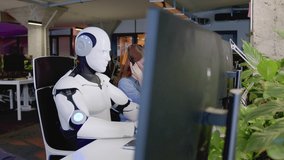 Side-view portrait futuristic white robot with artificial intelligence working in crowded office typing on keyboard using computer. Smart cyborg working with people in IT company. Technologies concept - Powered by Shutterstock - Get 15% off with code: PIKWIZARD15