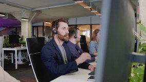 Close-up side view of group of professional people working in call center supporting customers. Attractive busy focused people talking wearing headphones in office using computers. - Powered by Shutterstock - Get 15% off with code: PIKWIZARD15