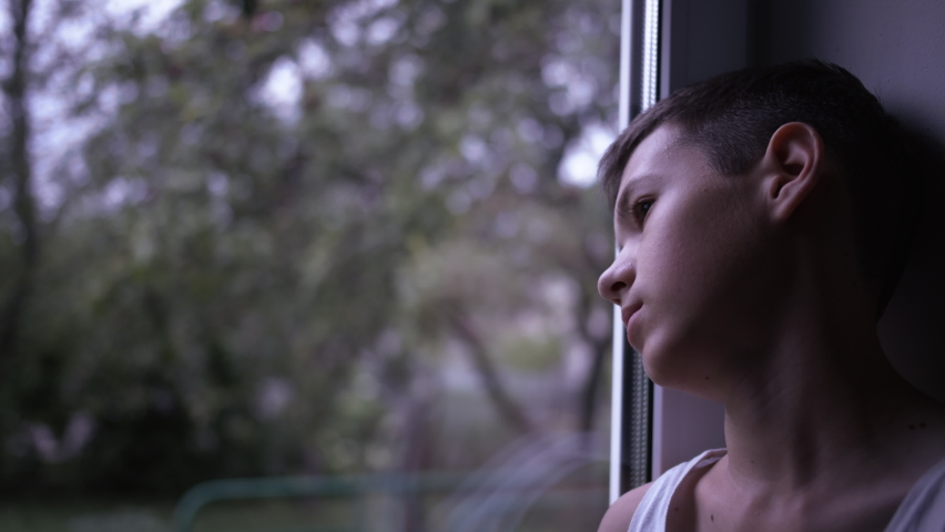 portrait of a sad boy looking out the window, loneliness, thinking about, steadicam shot