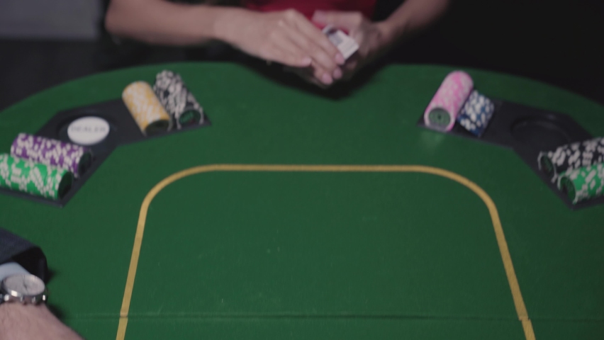 Young woman in a red dress hands out cards at a poker table. Starting to play in the casino