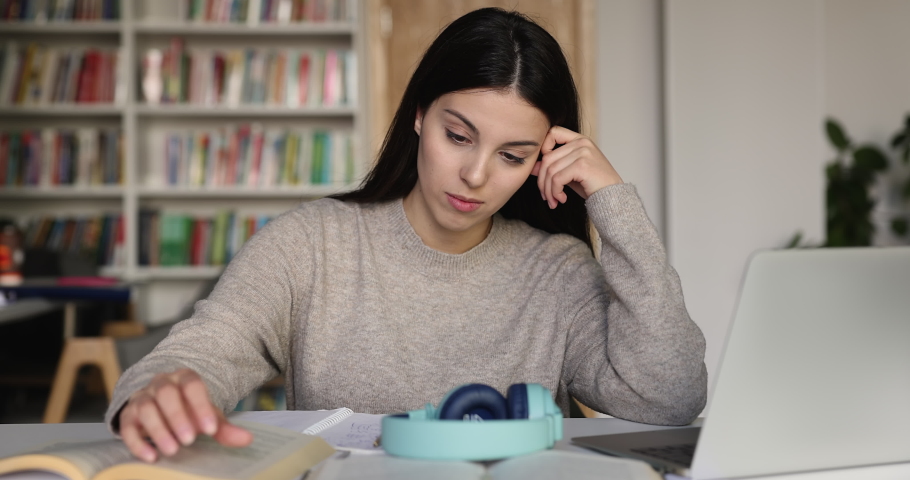 Student girl sit at desk in library feels bored, faced with difficult task, experiences lack of understanding while makes assignment, no ideas for essay or coursework. Information overload, studies Royalty-Free Stock Footage #1097839717