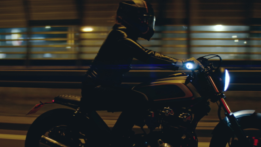 TRACKING Shot of a biker riding his custom built cafe racer motorcycle through city at night. Shot with 2x anamorphic lens
