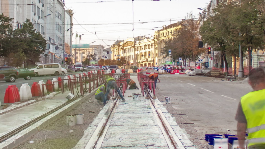 Tram rails at the stage of their integration into concrete plates on the road timelapse. Workers make mix and filling by liquid resin for reduction of vibration and noice. The process of