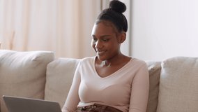 Young happy african american woman working on laptop at home, showing progress on screen to her loving boyfriend, tracking shot, slow motion, free space