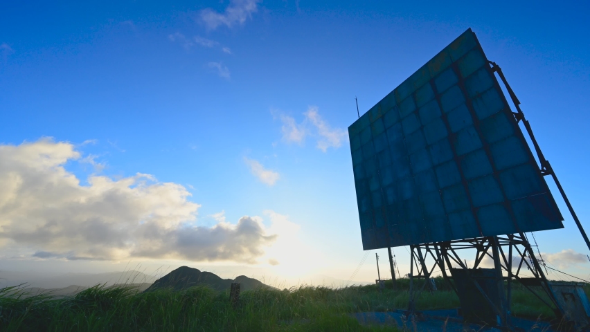 White clouds move over the mountain tops. A wooden billboard on the grass. The full course of the sunset. Caoshan, Ruifang District, New Taipei City, Taiwan.
