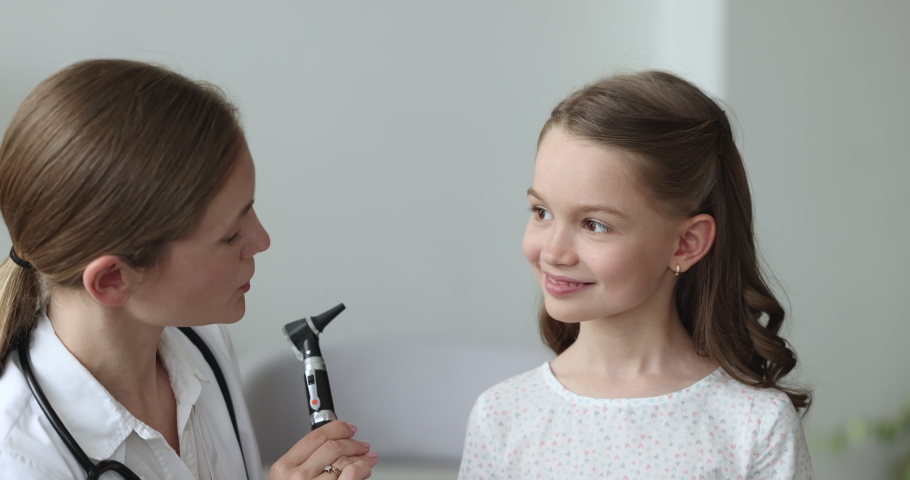 Close up of female doctor in white coat using otoscope instrument to check ear of little cute girl during visit in hospital. Woman laryngologist examining little patient. Otolaryngology, health-care Royalty-Free Stock Footage #1097845013