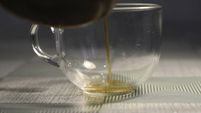 The video shows how hot tea is poured into a glass cup standing on the table.