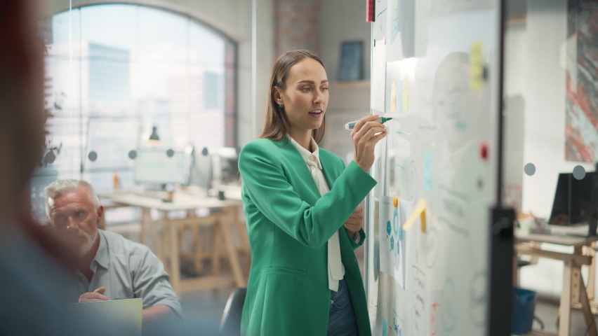 Woman Doing a Presentation in a Meeting Room at Office With her Team. Female Excutive Manager Presenting Company Growth Data and Marketing Strategy. Colleagues Asking Questions, Paying Attention
