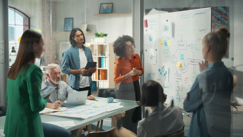 Diverse Modern Office: Black Businesswoman Leads Business Meeting with Managers, Talks, Explains Statistics, Uses a Whiteboard with Graphs, Big Data. Digital Entrepreneurs Work on eCommerce Project