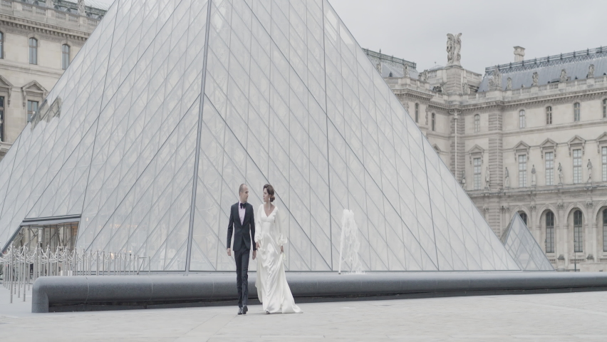 Wedding photography in tourist places. Action. A beautiful couple in smart suits walking around the square and posing for the camera.