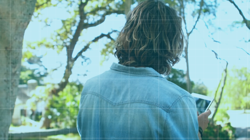 A man using a digital tablet in a park. Digitally generated, with animation of three blue statistic lines increasing and decreasing on a digital display. 