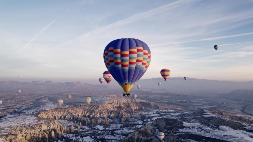 Aerial drone video of famous Hot air balloons flying over beautiful Cappadocia, Göreme, Turkey during the amazing sunrise in a snowy winter day. Royalty-Free Stock Footage #1097881897