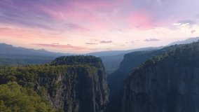 Aerial drone video footage of a large deep canyon. Sheer cliffs and green trees. Wildlife concept. Sunset background