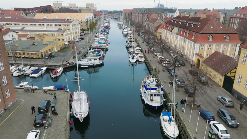 Copenhagen river in city downtown. Ships and boats anchored on the sides of narrow canal. Aerial drone footage