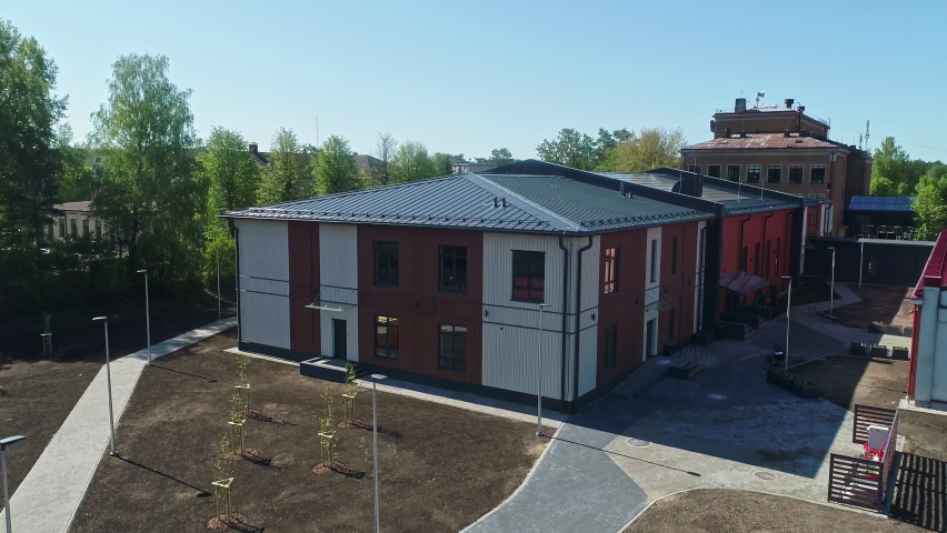 New construction of a school gymnasium with solar panels on the roof - ascending aerial view