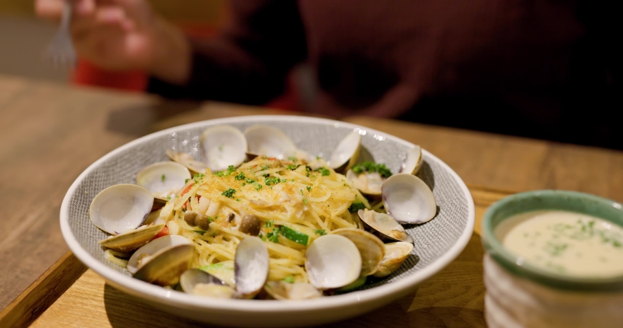 Woman eat fry pasta with clam in restaurant