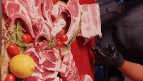 Vertical Screen: Butchers hands slicing steaks from raw pork meat. Man hands cutting pieces of pork meat for barbecue.