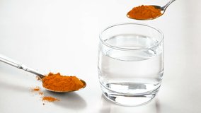 Mixing turmeric powder in a glass of water.