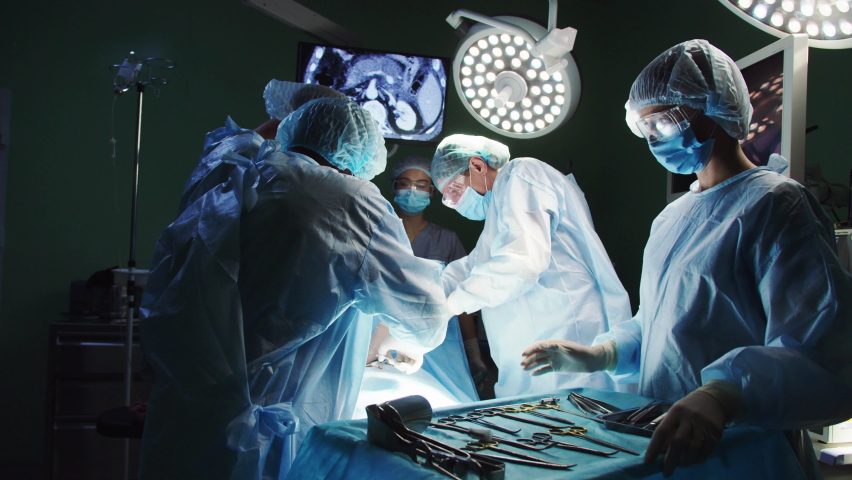 Side-view professional nurse giving instruments helping assisting surgeons performing operation. Group of multiethnic medical workers providing heart surgery in operation room wearing medical gowns. Royalty-Free Stock Footage #1097905457