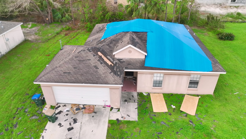 Top view of leaking house roof covered with protective tarp sheets against rain water leaks until replacement of asphalt shingles. Damage of building rooftop as aftermath of hurricane Ian in Florida Royalty-Free Stock Footage #1097905573