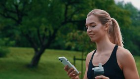 Close up of the sporty caucasian woman is going in the park, using smartphone holding the sport water bottle, wearing smartwatch. Sport and people concept - Powered by Shutterstock - Get 15% off with code: PIKWIZARD15