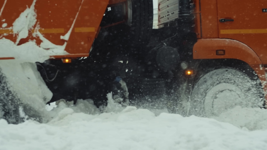 Snow removal by snow plow machine, slow motion close up shot. Machinery snow removal
