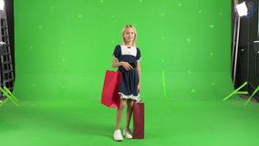 Young girl in casual clothes with shopping bags on a Green Screen, Sale day. Woman buyer on Chroma Key. 4k UHD front view video