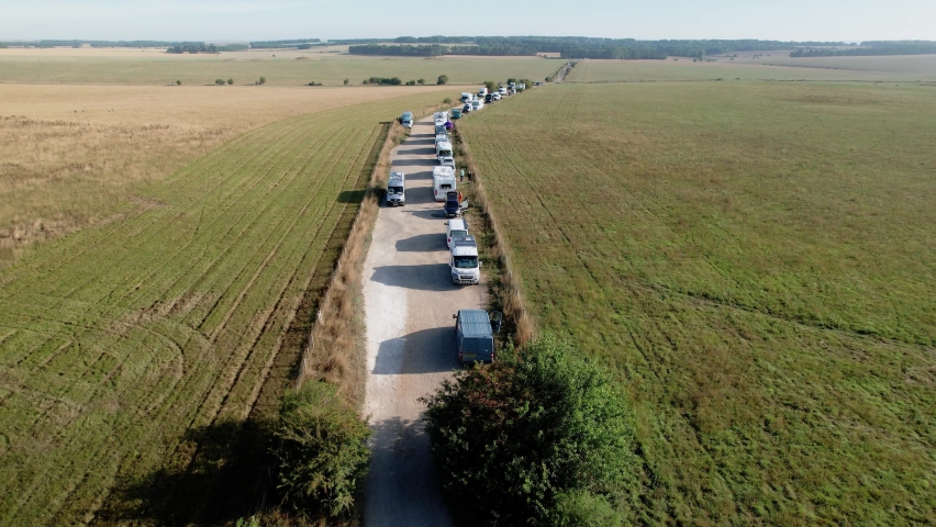 Aerial view over long line of campervan vehicles parked at Stonehenge, Salisbury famous landmark