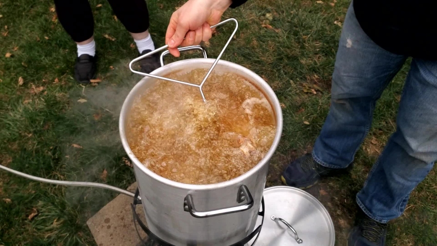 Pulling with hook thirty pound of whole Turkey while being deep fried in three plus gallons of peanut and soy oil. Royalty-Free Stock Footage #1097927257