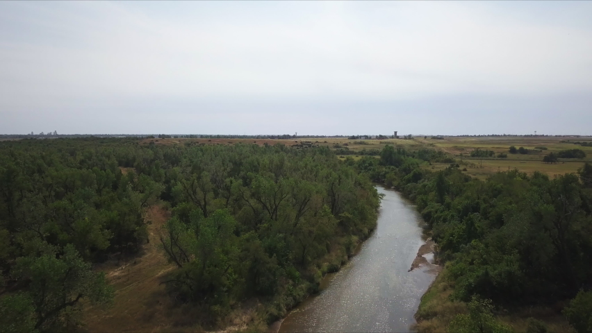 Backwards dolly shot above a small river flowing in the countryside of Georgia