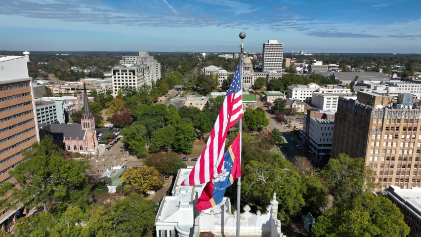 USA and Mississippi State flag with capitol in distance. Aerial in Jackson MS. Poorest state in America.