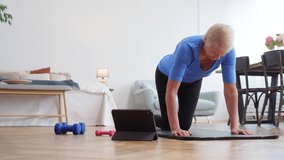 elderly woman doing exercises with an online trainer in her living room.