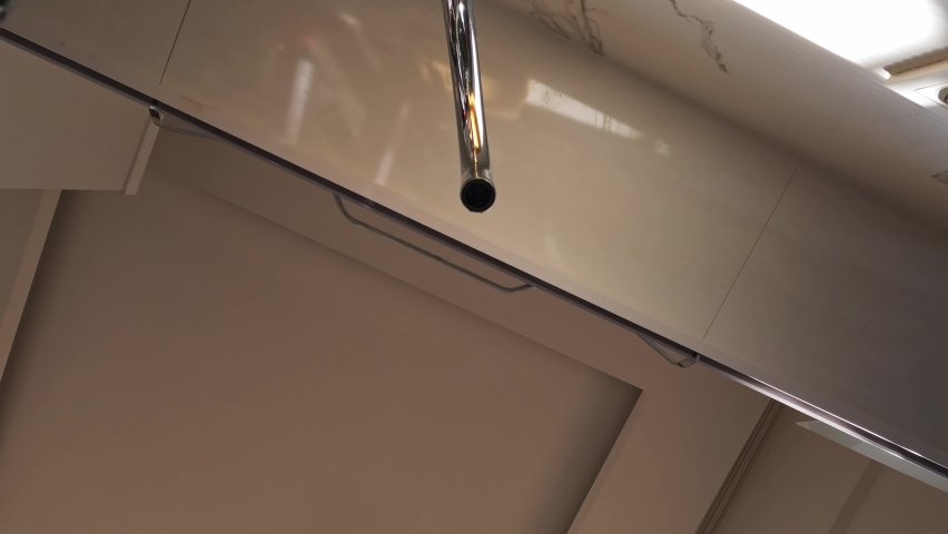young woman open faucet and wash pear fruit with her hands under running water. Girl wash fruit for salad or to eat fresh, view from bottom of sink, water dripping onto camera.