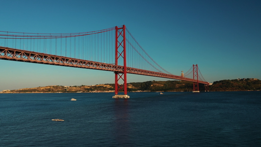 The 25 de Abril Suspension Bridge over Tagus river in Lisbon, the capital of Portugal, with busy traffic on the bridge during sunset hours. Royalty-Free Stock Footage #1097942407