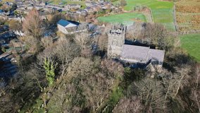 Aerial drone video footage of the small village of Denshaw, a typical rural village in the heart of the Pennines. Showing old houses road junction, village church and vast moorlands..
