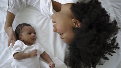 Closeup portrait of beautiful young African American mother day girl kiss healthy newborn baby sleep in bed flat lay copy space. Healthcare medical love black woman lifestyle mother's day, top view స్టాక్ వీడియో