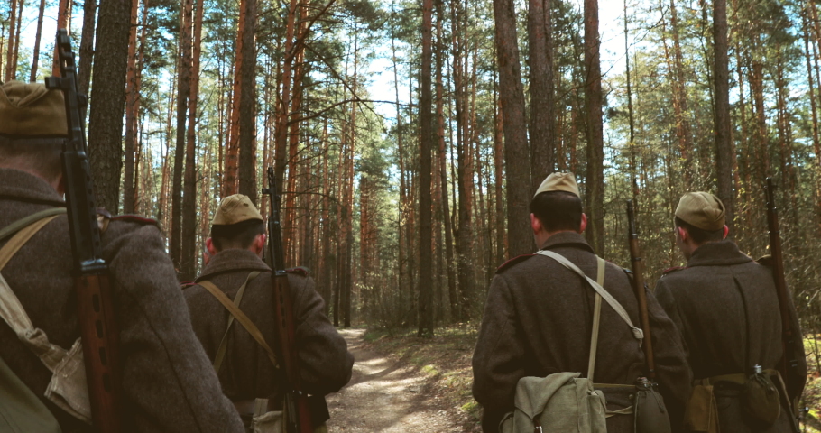 4K Squad Men Dressed As World War II Russian Soviet Red Army Soldiers Marching Through Spring Forest In Sunny day. Soldier Of WWII WW2 Times