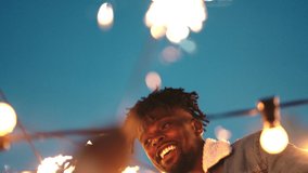 Black man, dancing and sparkler in party celebration for new year, event or night festival in the outdoors. Happy African American male with friends enjoying firework dance, music and nightlife - Powered by Shutterstock - Get 15% off with code: PIKWIZARD15
