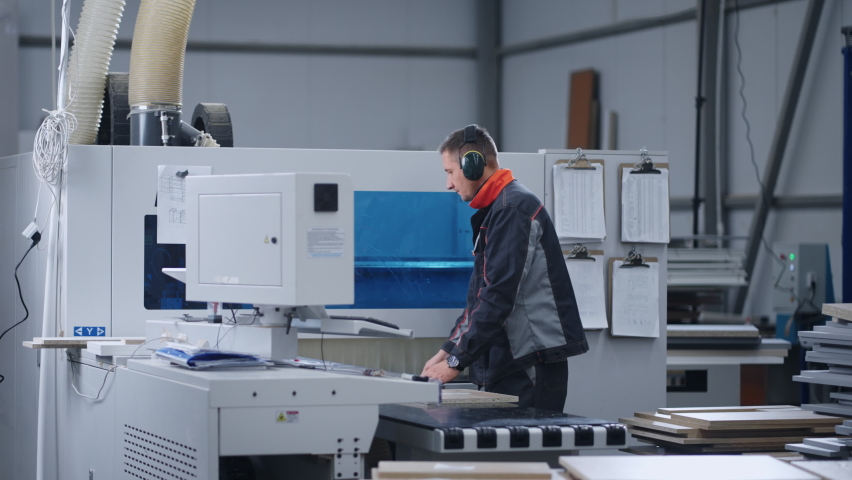 modern furniture factory, milling process in workshop, man is programming woodworking machine