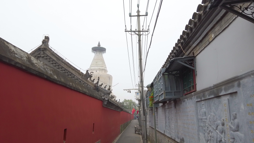Walking through narrow Hutong lane with background of pagoda, Beijing, China.