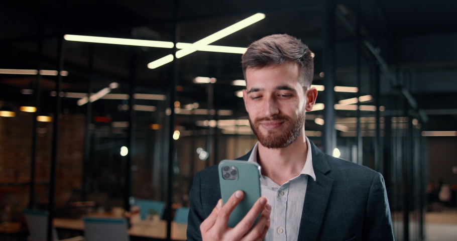 Close-up of green chroma key on smartphone display to insert advertisement for your product, service or application. Middle-aged man out of focus stretches his hand with smartphone display into camera