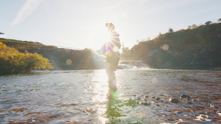 Fisherman casts the line on a river at sunrise. Angler stands in waders in the river and fishing on fly Royalty-Free Stock Footage #1097984623