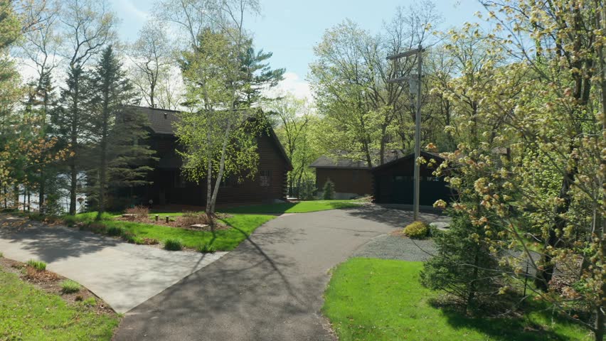 Driveway leading to beautiful lakeside cabin in a forest during a summer day
