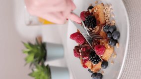 cut soft waffles with red cherry and red berries on a serving board, cooking with soft sweet waffles and cherry jam. vertical video