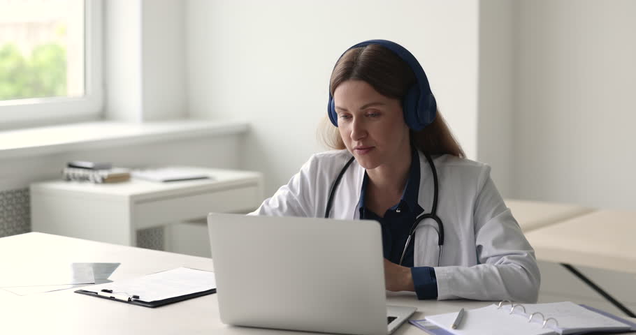 Professional medical worker talks to client through videoconference seated at workplace, using easy and convenient telemedicine application and laptop. Virtual consultation from qualified gp doctor Royalty-Free Stock Footage #1098002625