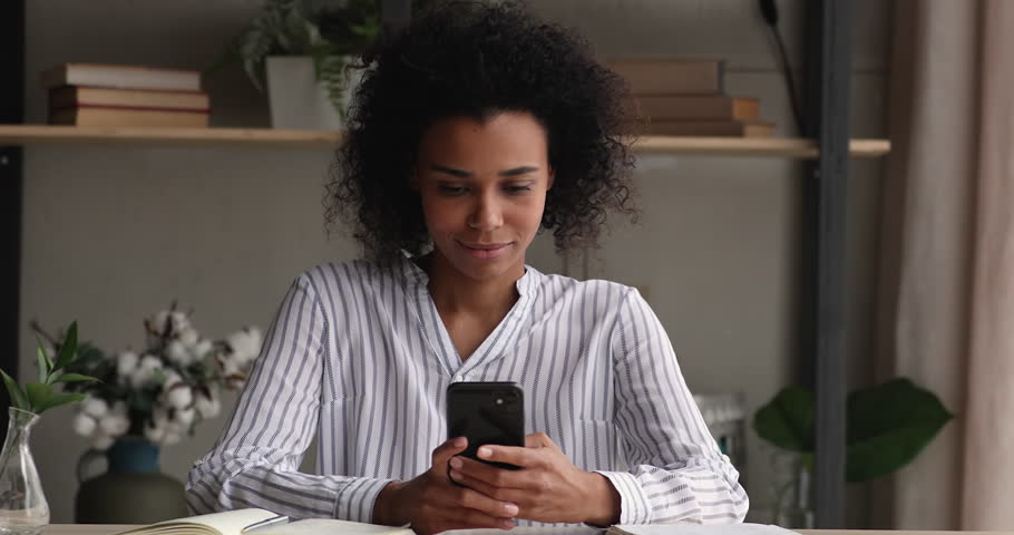 Distracted from studying happy millennial African American woman in playing mobile games, web surfing information, watching funny photo video content in social network, communicating or shopping. Royalty-Free Stock Footage #1098004941